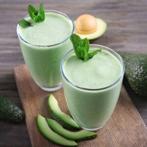 avocado mint smoothies with mint garnish and avocado slices on the side